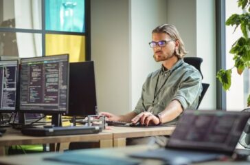 Male Data Scientist Coding on Desktop Computer in Creative Office Space. Caucasian Man Scraping Digital Information From Opened Sources in Internet For Artificial Inteligence Software Development.
