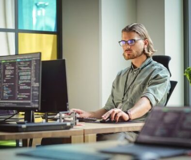 Male Data Scientist Coding on Desktop Computer in Creative Office Space. Caucasian Man Scraping Digital Information From Opened Sources in Internet For Artificial Inteligence Software Development.