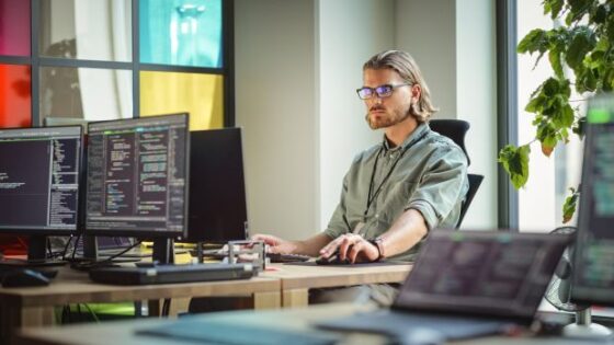 Male Data Scientist Coding on Desktop Computer in Creative Office Space. Caucasian Man Scraping Digital Information From Opened Sources in Internet For Artificial Inteligence Software Development.